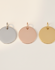 Three round steel pendants in silver, rose gold, and gold on a white background