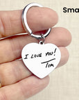 Heart-shaped keychain with 'I Love You! Tim' engraving held in a hand.
