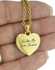 Gold heart pendant with the inscription 'You Are My Sun Shine' held in a hand