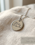 Silver necklace with engraved pendant on a textured surface