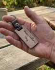 Hand holding a wooden keychain with 'Happy Father's Day' text on a wooden table.
