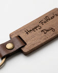 Wooden keychain with leather strap and 'Happy Father's Day' engraving on a white background