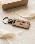 Wooden keychain with 'Happy Father's Day' engraving on a light fabric background