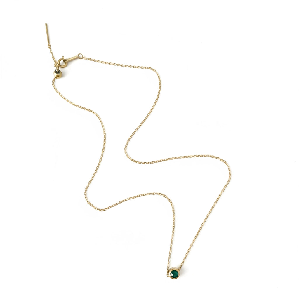 Gold necklace with a green gemstone pendant on a white background