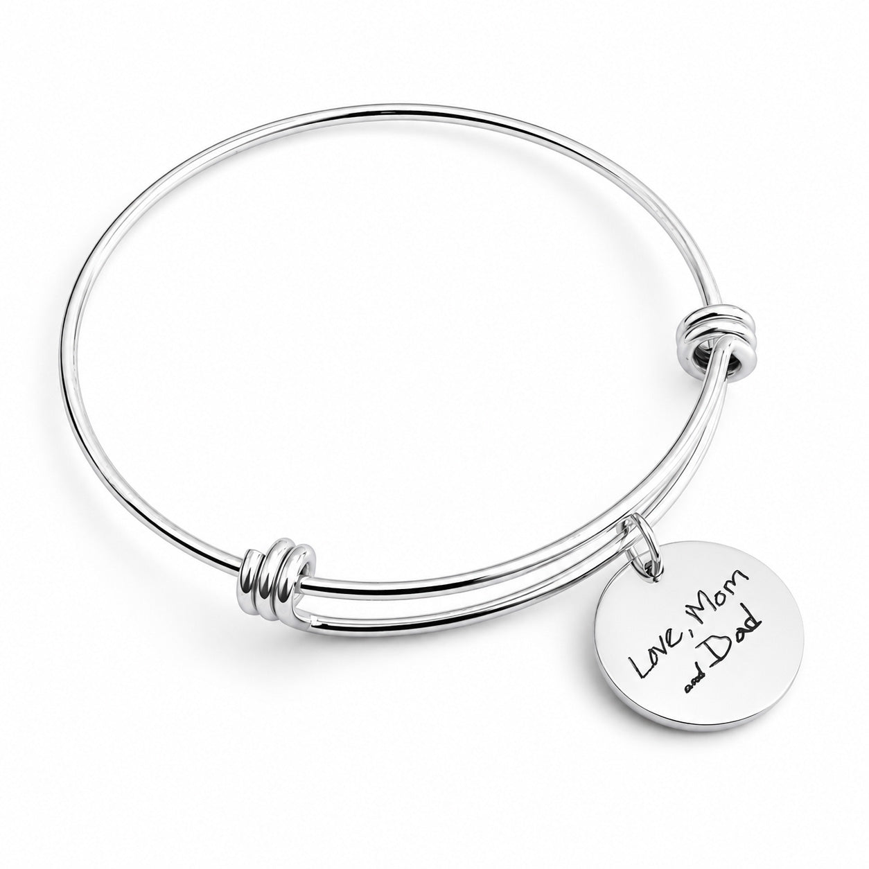 A silver-toned metal expandable wire bangle bracelet with a round engraved disc charm that reads 'Love, Mom and Dad' on a clean white background.