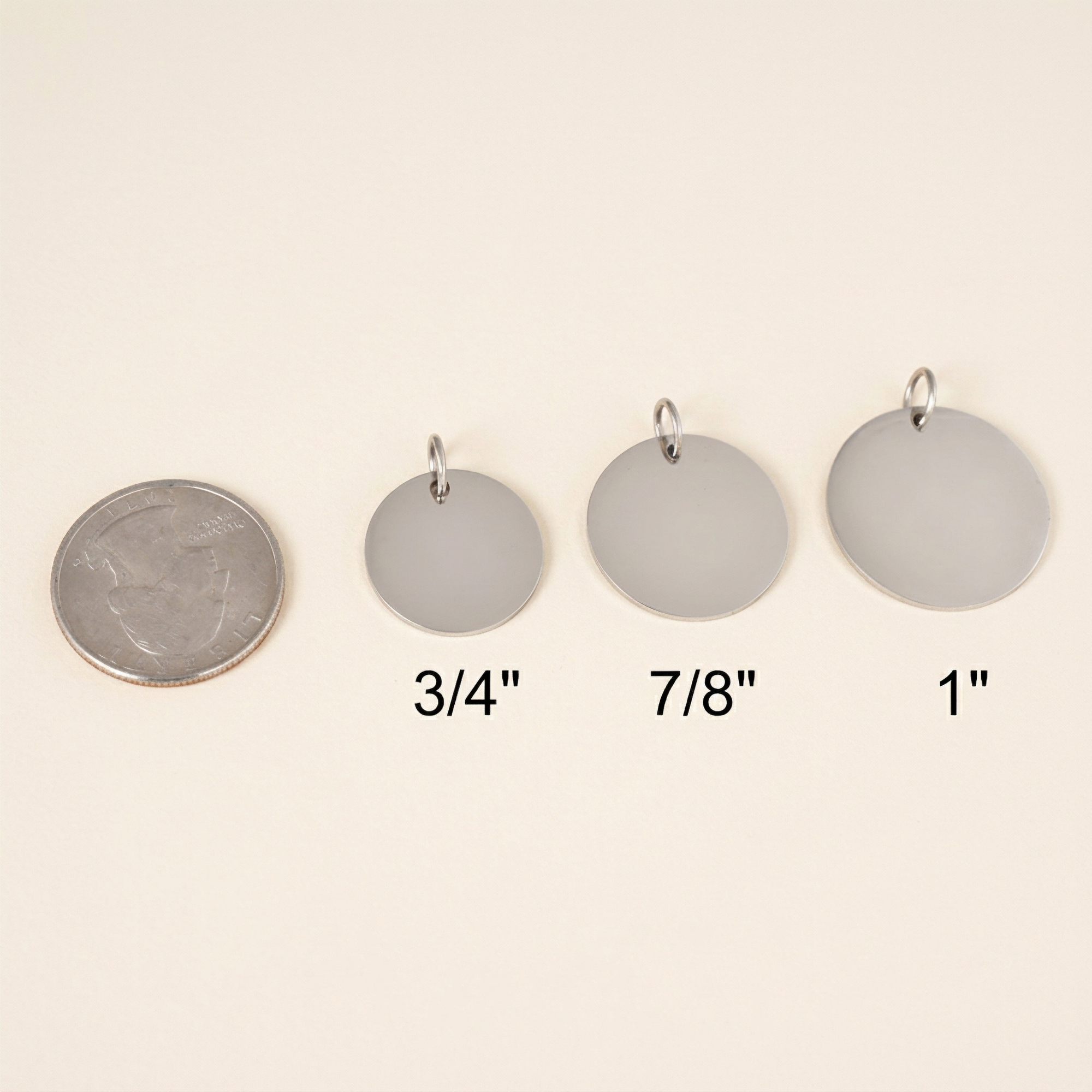 Set of four round metal handwriting pendants with measurements on a beige background
