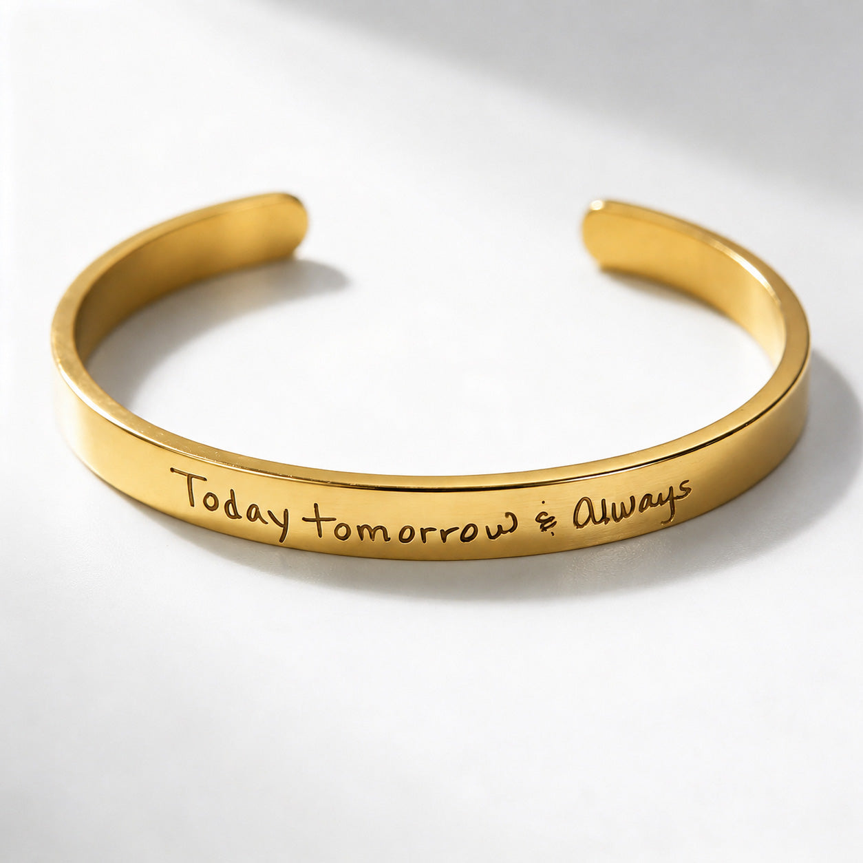 A polished gold cuff bracelet engraved with the words 'Today, tomorrow &amp; Always' in a cursive script, displayed on a clean white background with soft shadows.