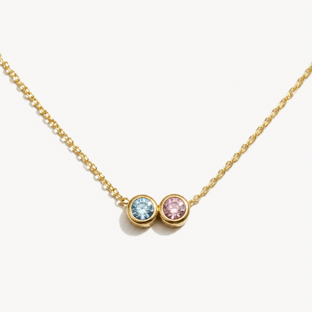Gold necklace with two gemstones on a white background