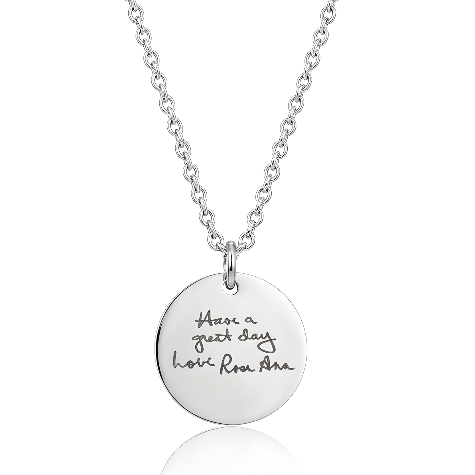 Silver necklace with a round pendant engraved with handwriting on a white background.