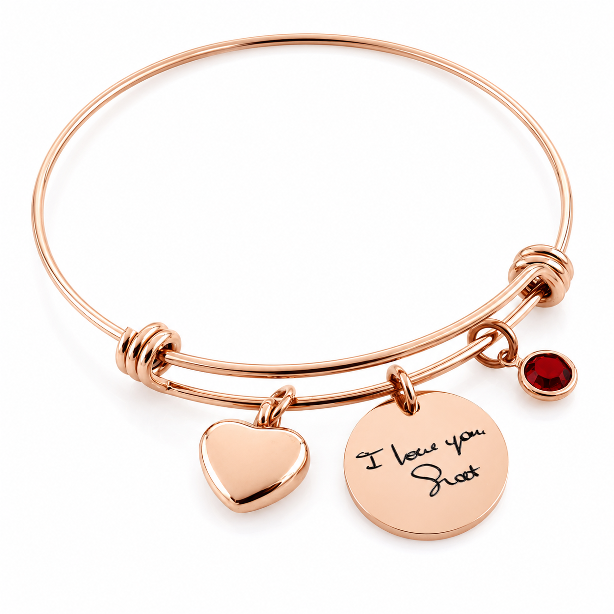 Rose gold bangle bracelet with a heart charm, a round disc charm engraved with 'I love you Scott', and a small red gemstone accent, shown on a white background.