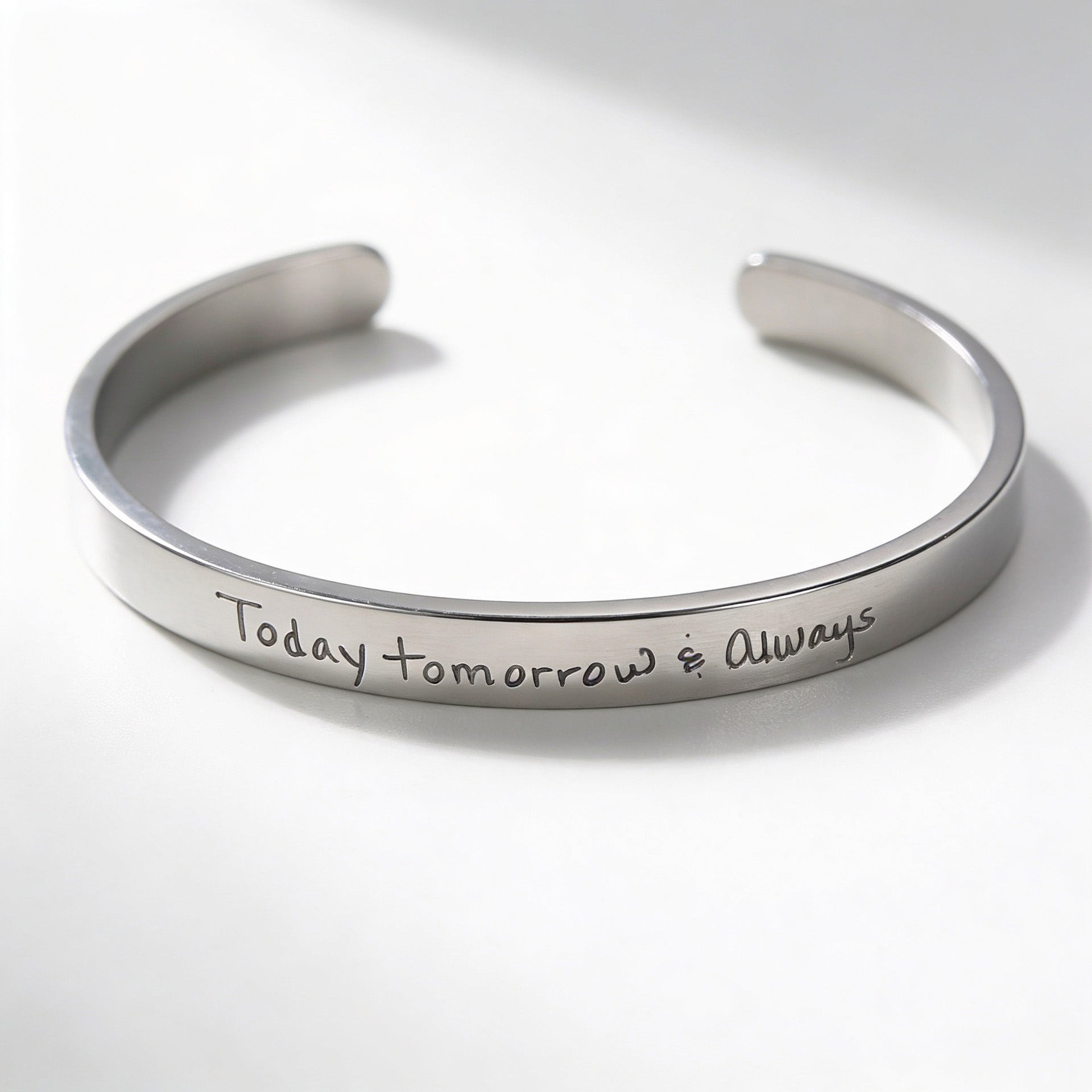 A polished silver cuff bracelet engraved with the handwritten phrase 'Today tomorrow &amp; Always' on a clean white background.